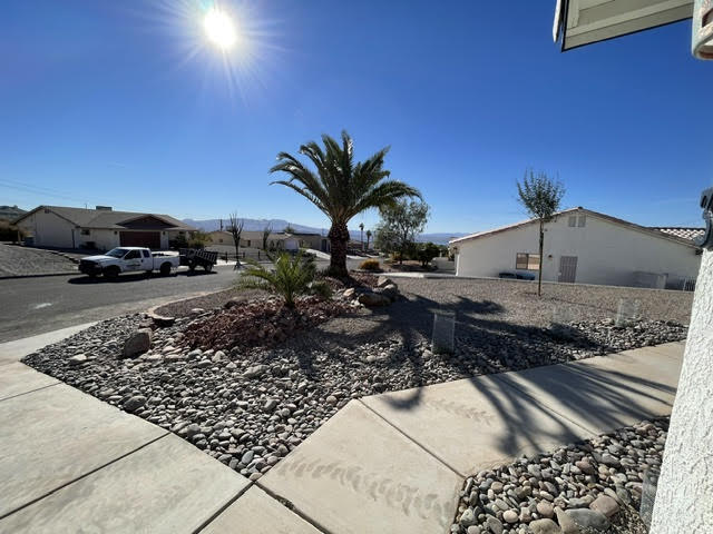 River rock corner bed with a palm and desert plants on a Lake Havasu City street